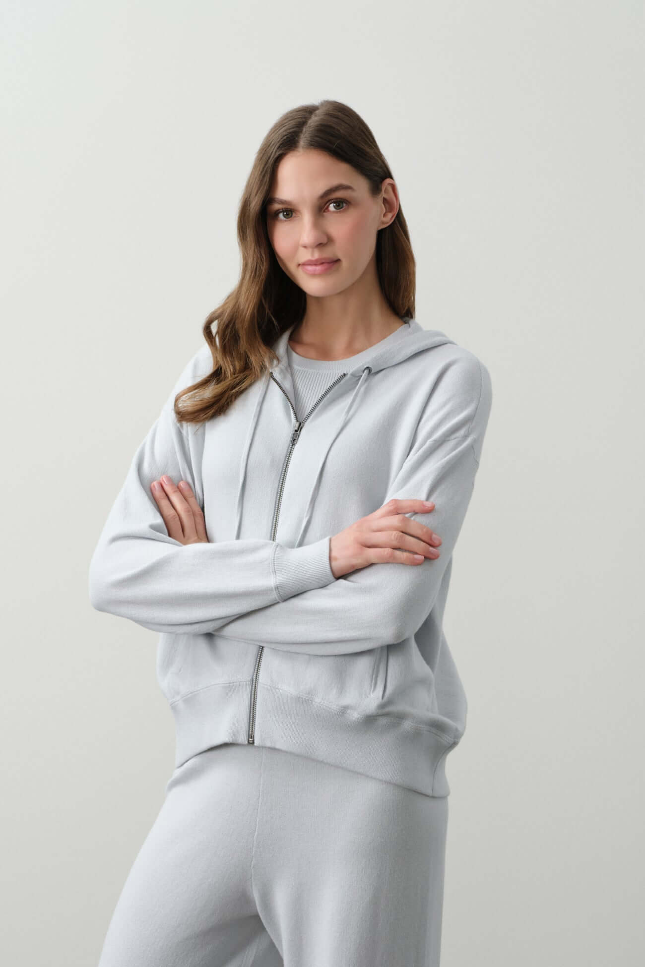 Woman wearing a light grey hoodie and matching bottoms from the Sets Separates collection.