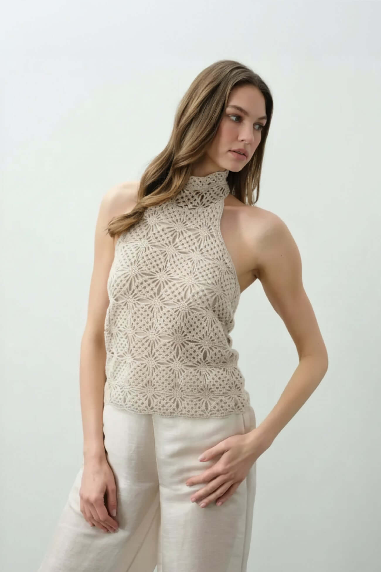 Model wearing a stylish knitted halter top from the Tops collection, showcasing a unique floral design.