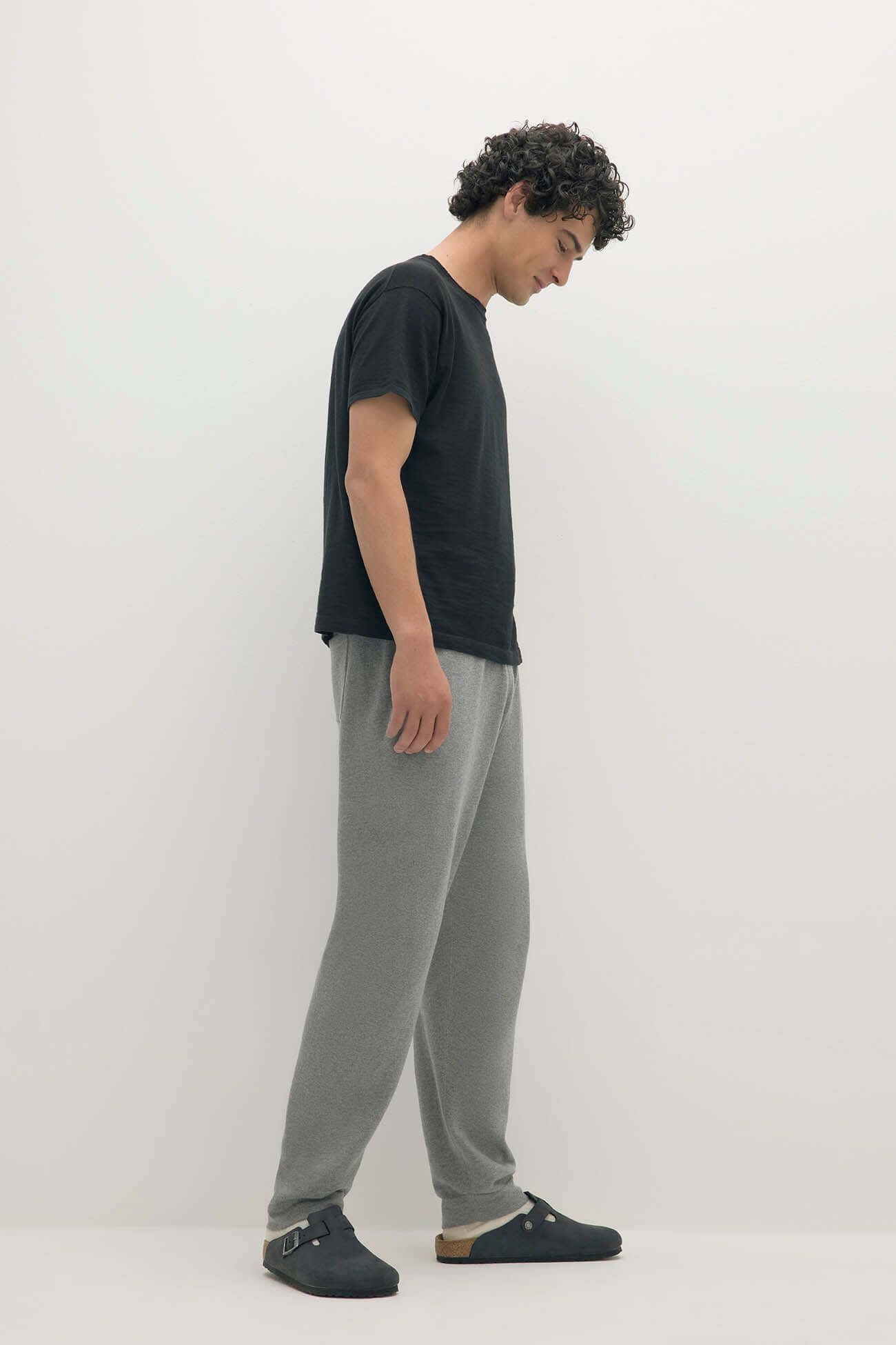 Man wearing black t-shirt and grey sweatpants in comfortable Loungewear style.